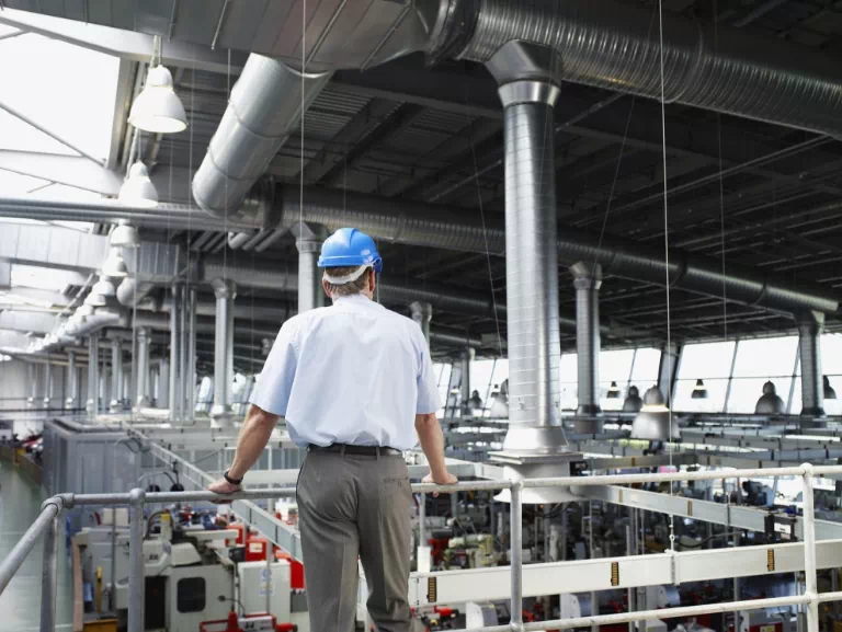 Człowiek w niebieskim kasku patrzący na fabrykę